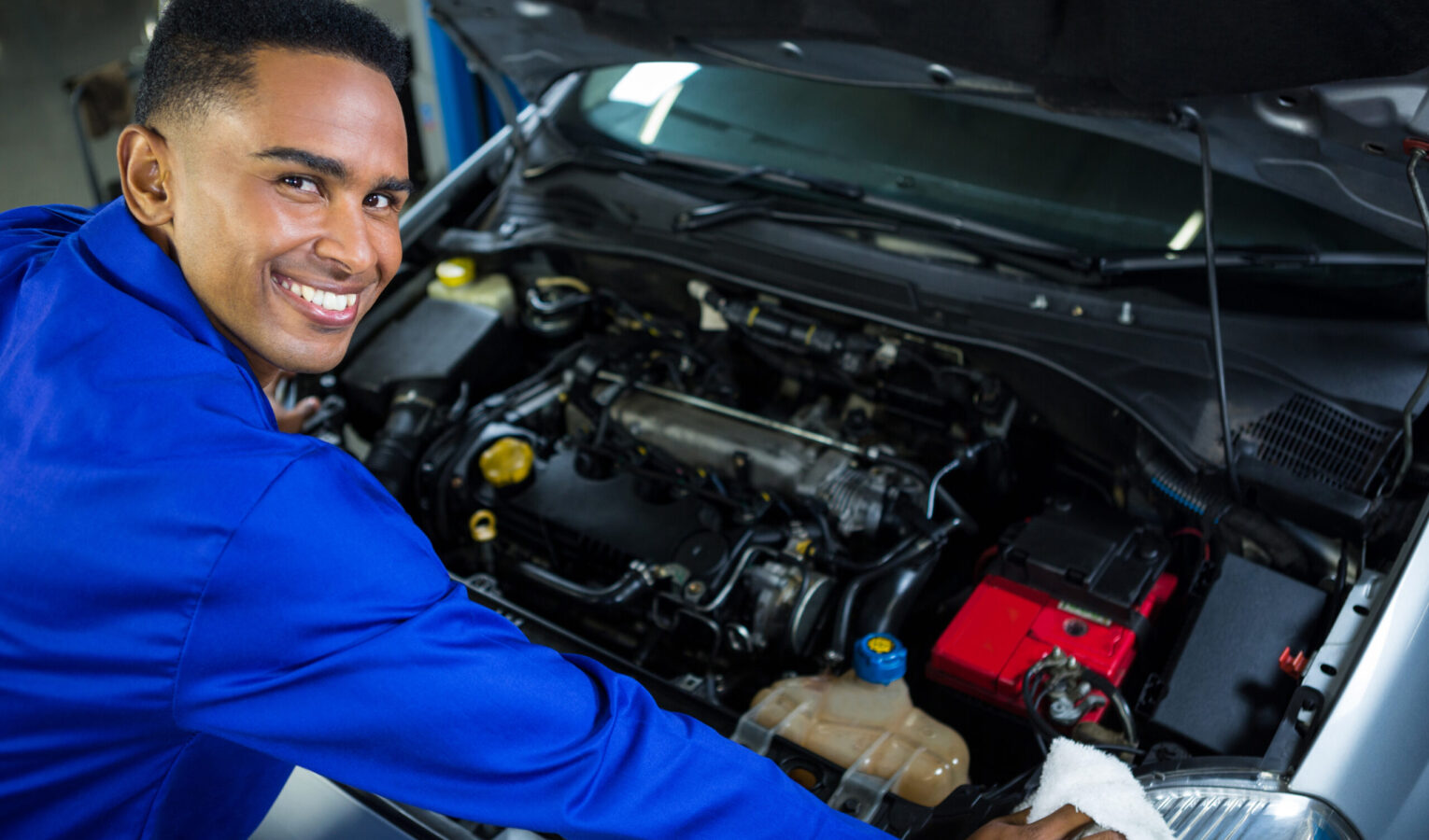 Portrait of happy mechanic servicing car at repair garage