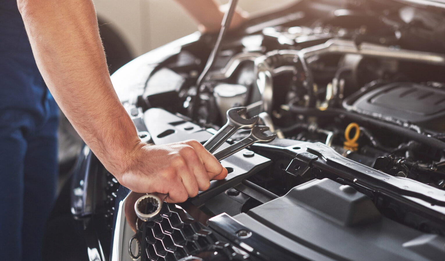 Picture showing muscular car service worker repairing vehicle.